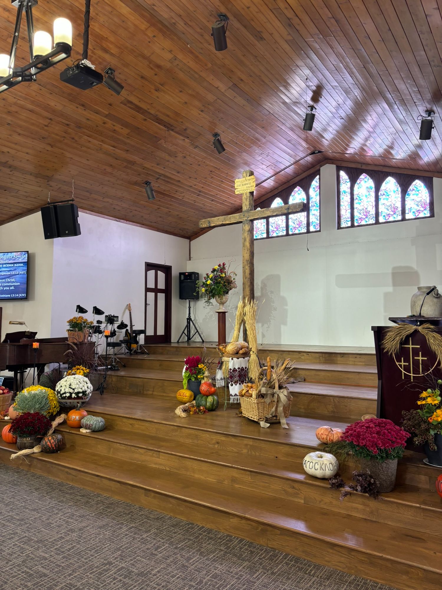 Church sanctuary decorated for harvest with pumpkins and flowers around the cross